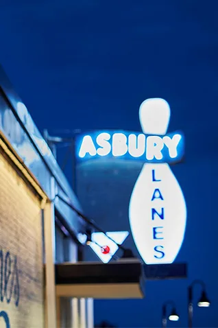 Asbury Lanes mural on brick wall and neon sign at night in Asbury Park NJ