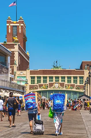 Backpackers on Asbury Park Boardwalk with the historic Convention Hall and Paramount Theatre in background