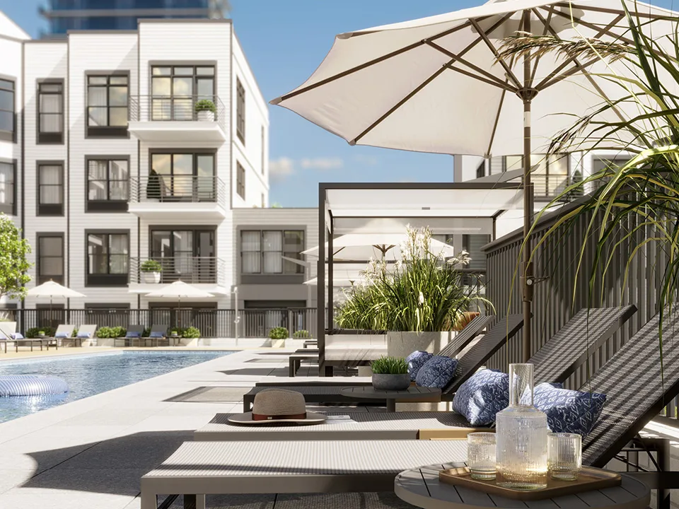 SURFHOUSE lounge seating under an umbrella with swimming pool and Asbury Park rental apartments in the background