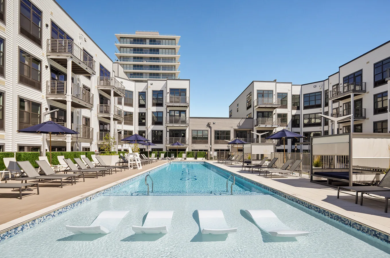 SURFHOUSE swimming pool and outdoor lounge area with chairs in the water surrounded by Asbury apts