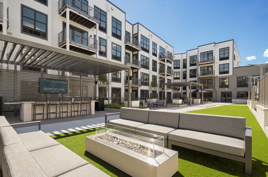 https://surfhouseasburypark.com/wp-content/uploads/2025/09/surfhouse-courtyard-1.webp SURFHOUSE outdoor courtyard with bar seating, sofa, and firepit outside Asbury Park Luxury Apartments.