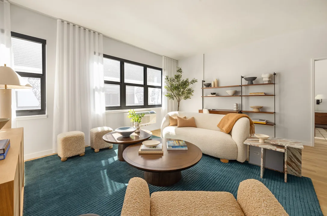 https://surfhouseasburypark.com/wp-content/uploads/2025/09/surfhouse-room.webp Asbury Park Apartment with bouclay furniture, teal carpet and decorated shelf in luxury residence.